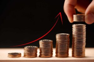 Illustrazione monete in pile sempre più alte e freccia che segnala un aumento