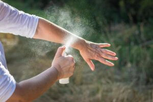 Donna che si spruzza uno spray antizanzare sul braccio