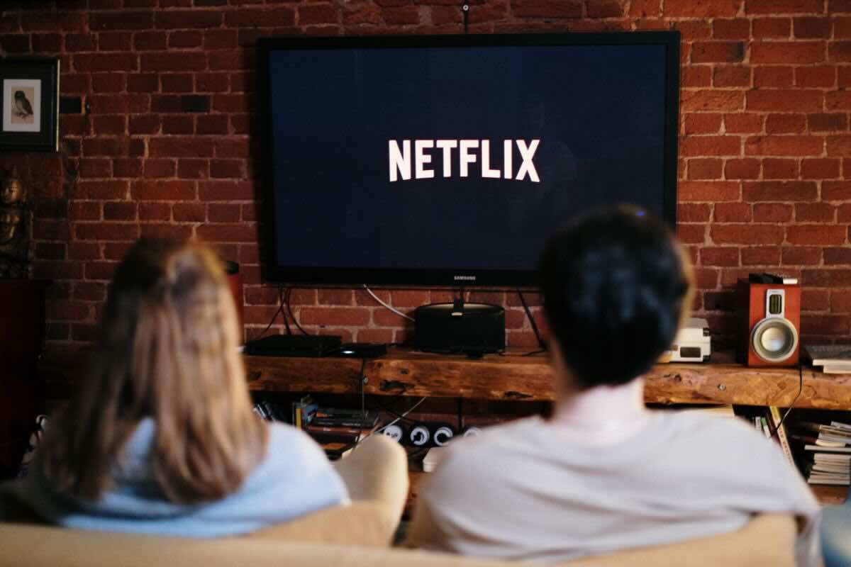 Coppia guarda schermo con scritta Netflix