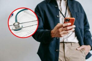 Un uomo che invia un sms con un telefono rosso e, in evidenza, uno stetoscopio