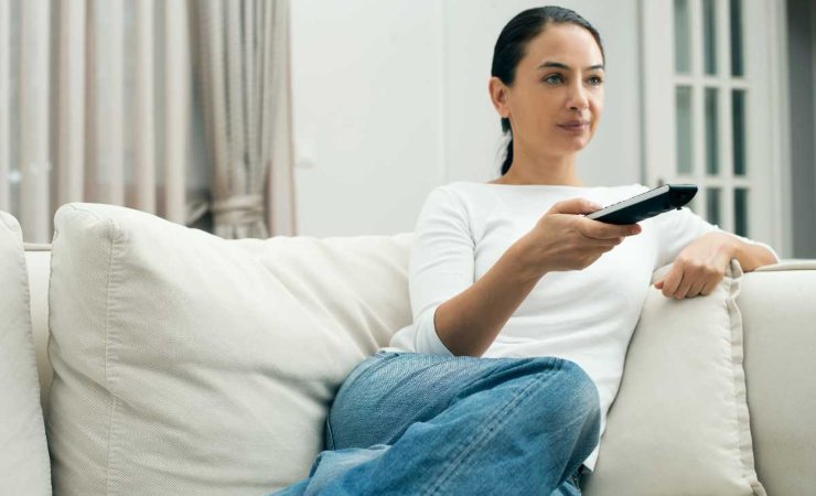Donna sul divano con telecomando