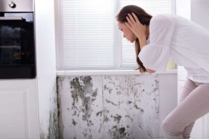 donna che guarda muffa sul muro