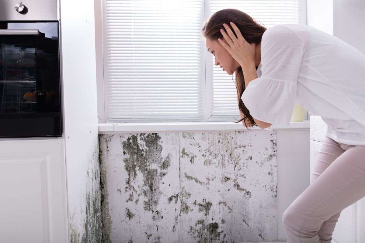 donna che guarda muffa sul muro