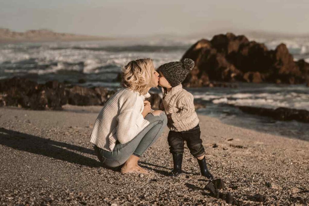 Una madre bacia il figlio piccolo sulla spiaggia