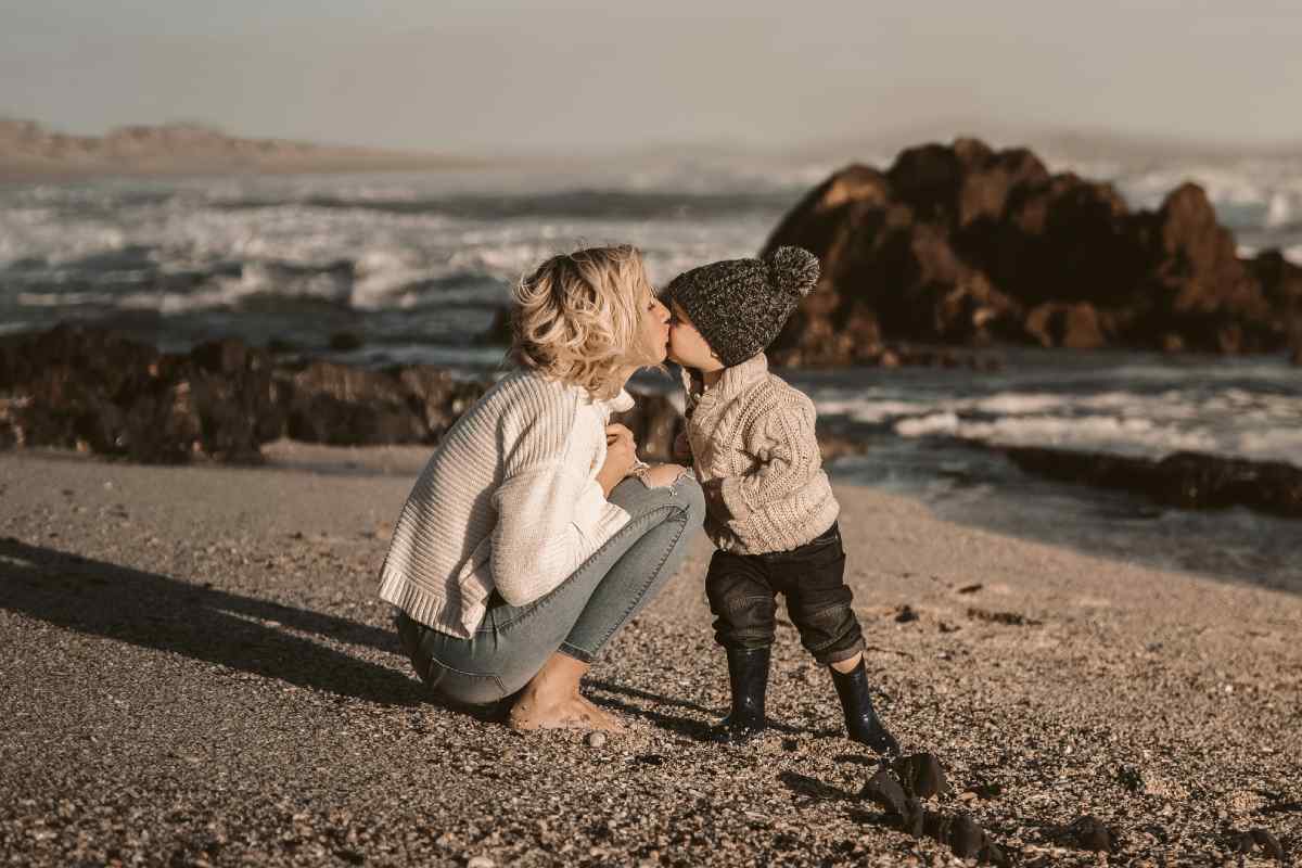 Una madre bacia il figlio piccolo sulla spiaggia