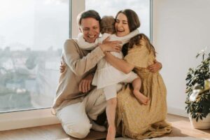 Padre e madre abbracciano un bimbo piccolo