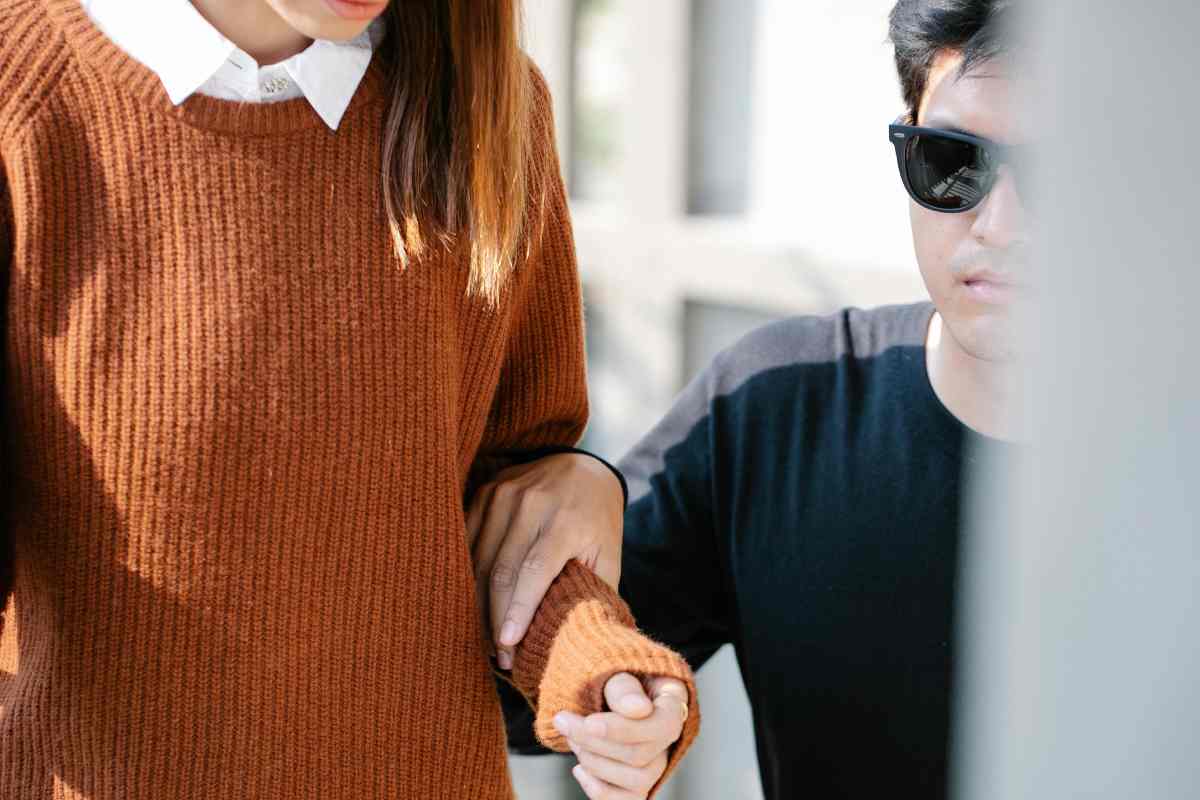 Una cargiver che accompagna un non vedente