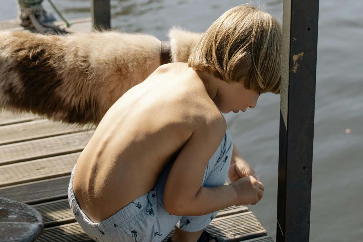 Un bambino biondo al mare con un cane
