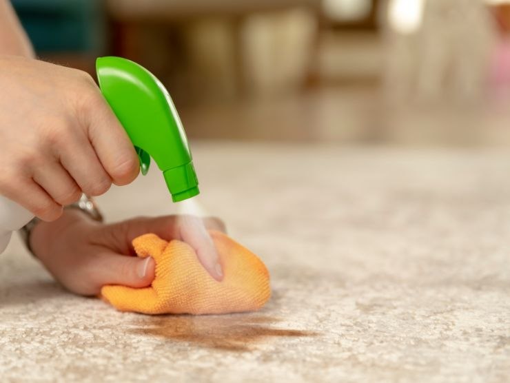 persona che spruzza spray per pulire il tappeto
