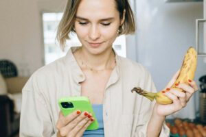 Ragazza con una banana in una mano e un telefonino nell'altra