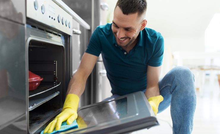 uomo che pulisce il forno