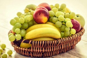 Un cesto con banane, uva e pesche