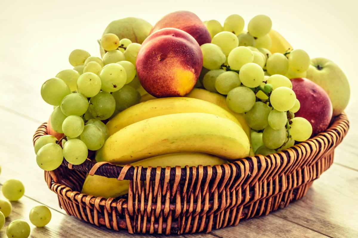 Un cesto con banane, uva e pesche