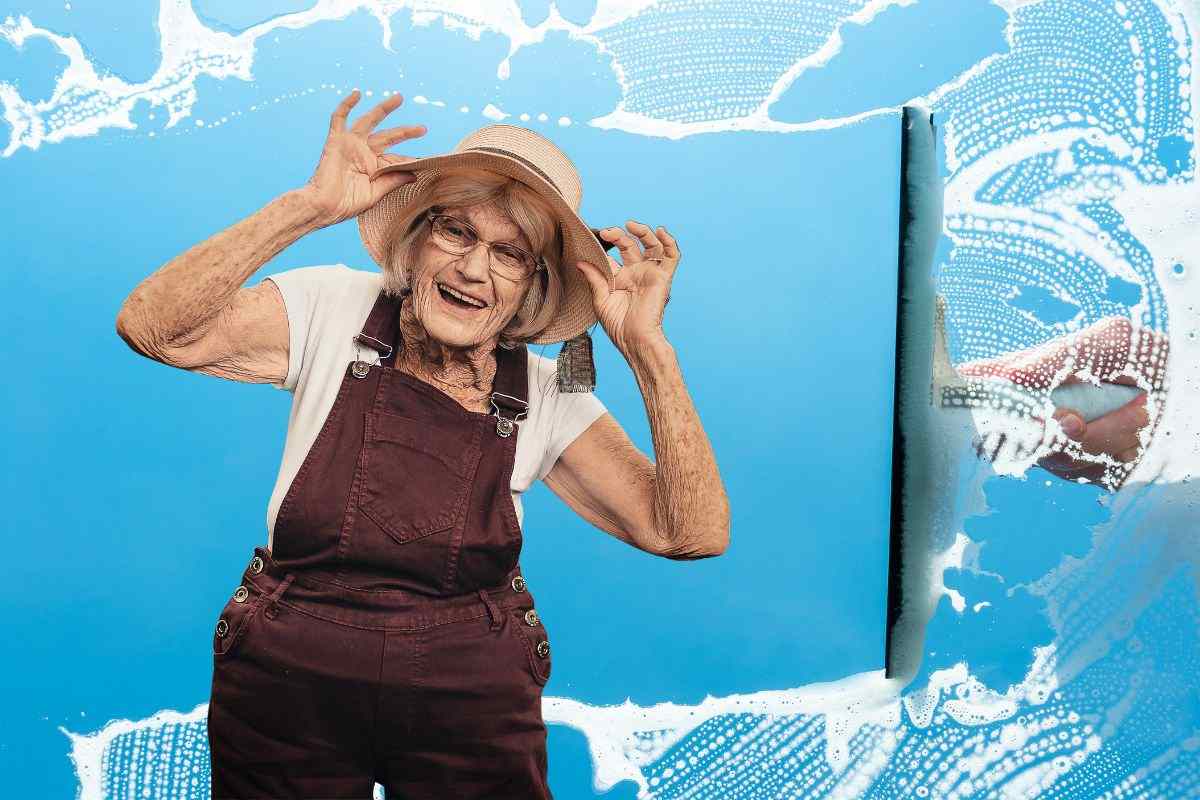 persona matura e mano che pulisce vetri