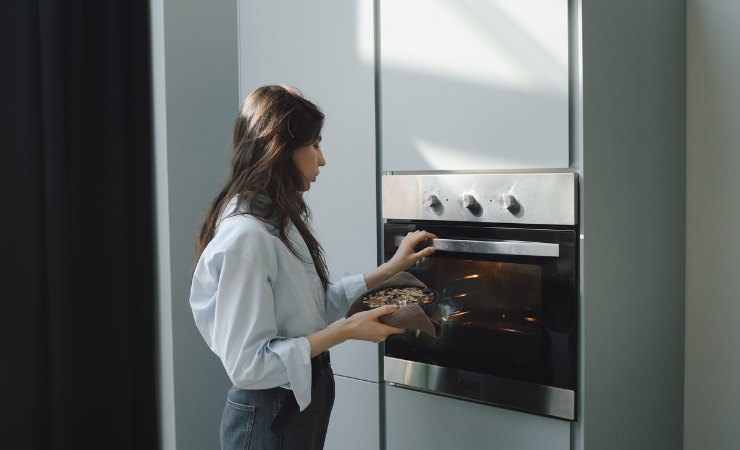 donna mette cibo in forno