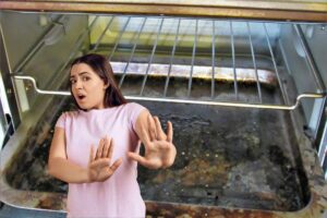 donna disgustata dallo sporco che c'è nel forno