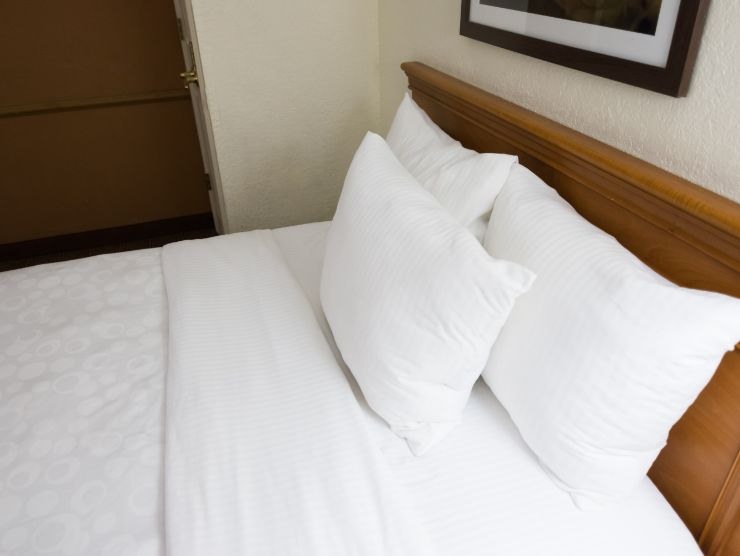 letto fatto in modo perfetto con lenzuola e cuscini bianchi