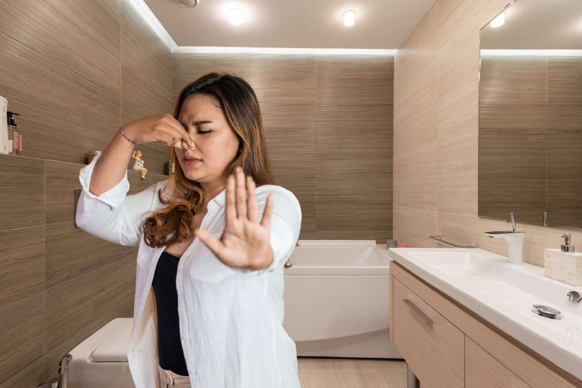donna che si tappa il naso per i cattivi odori nel bagno