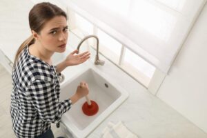 donna che tenta di sturare lo scarico