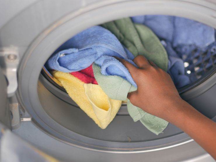 mano che prende dei vestiti dalla lavatrice